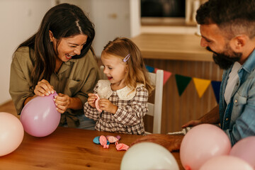 Parents and child blowing up balloons for celebration
