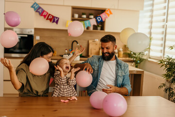 Family celebrating a child's birthday with balloons