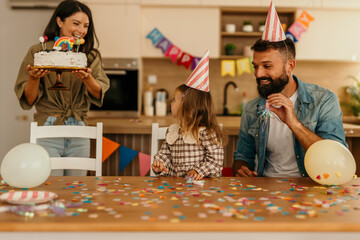Family celebrating birthday with cake and party hats
