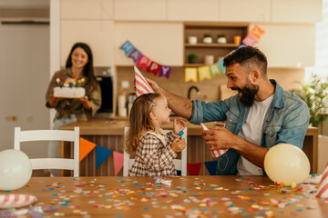 Family celebrating child's birthday at home with cake