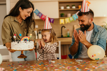 Family celebrating birthday with cake and confetti