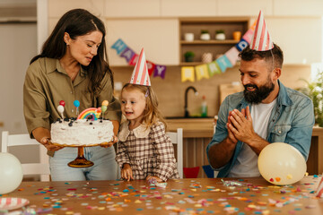 Family celebrating child's birthday at kitchen table
