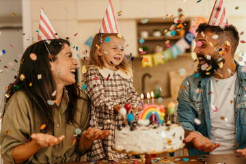 Family celebrating a joyful birthday party with confetti