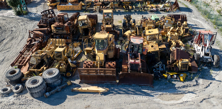 Aerial view of the graveyard of yellow and rust-colored heavy machinery and tires creates a stark contrast against the pale, dusty ground, Nanclares de la Oca, Basque Country, Spain.