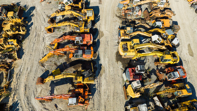 Aerial view of a multitude of excavators, a symphony of yellow and orange hues against a sandy backdrop, creating a geometric pattern from above, Nanclares de la Oca, Basque Country, Spain.