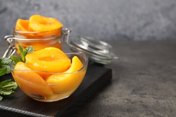 Pickled peaches and mint leaves on grey table, closeup. Space for text © New Africa