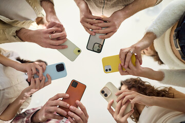 People in a circle use smartphone phones together. A diverse group shares screens to boost...