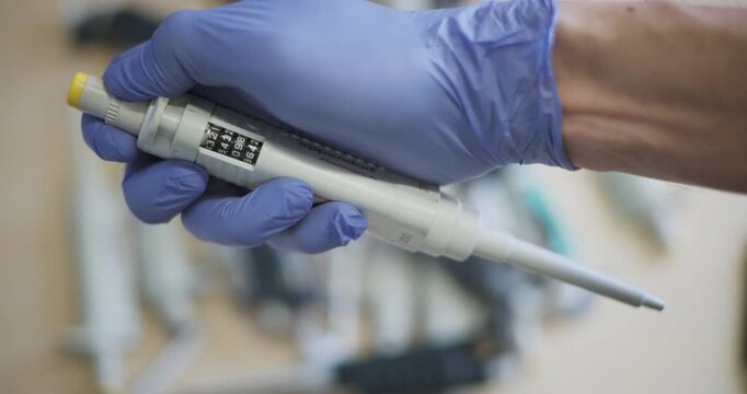 Scientist hand holding adjustable micropipette during laboratory experiment preparation, research lab footage