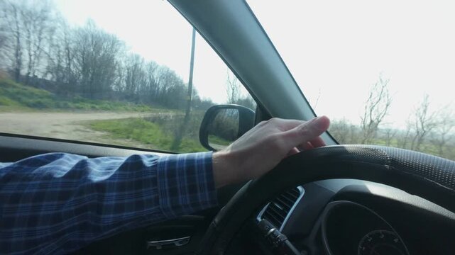 closeup of man's hand on steering wheel while driving