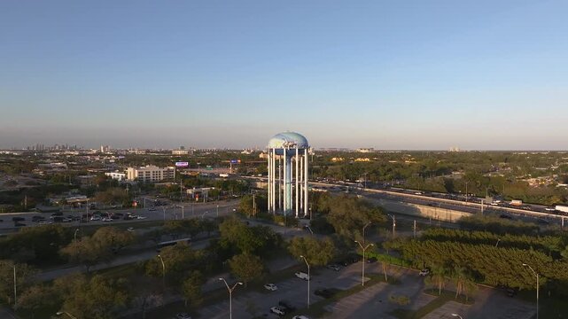 Aerial view of the iconic water tower, a beacon amidst the lush greenery and bustling I-95 highway, reflecting the sky's soft hues, Hollywood, Florida, United States.
