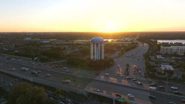 Aerial view of traffic flowing on I-95 highway and a water tower standing tall amidst the cityscape at sunset, Hollywood, Florida, United States.