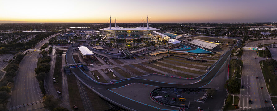 Miami Gardens, USA - 23 February 2026: Aerial view of Hard Rock Stadium and the vibrant Formula 1 Miami International Autodrome under a fading sunset sky.