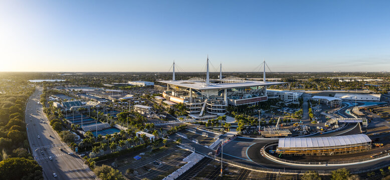 Miami Gardens, USA - 23 February 2026: Aerial view of Hard Rock Stadium bathed in the warm glow of the setting sun, juxtaposed against the sleek lines of the race track.
