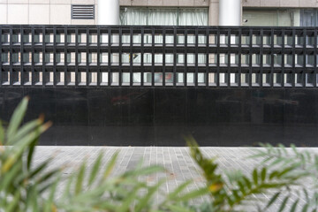 Naklejka premium Black grid fence in front of modern building exterior with glass windows and columns
