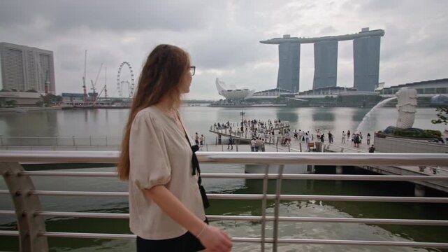 Beautiful Caucasian woman walking along the waterfront in Singapore. Cityscapes with modern architecture, Marina Bay, travel to Asia.