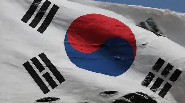 Torn South Korean Flag Waving in Wind Against Clear Blue Sky