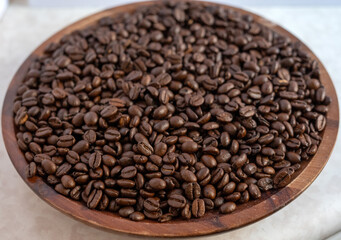 Fototapeta premium Close-up macro of roasted dark coffee beans filling a wooden bowl