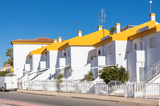 A bright sunny day in Torrevieja, Spain showcasing white buildings with yellow roofs and palm trees against a clear blue sky