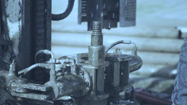 Close-up real video of a geotechnical drilling rig rotating and pushing a pipe into soil during ground investigation for construction engineering.