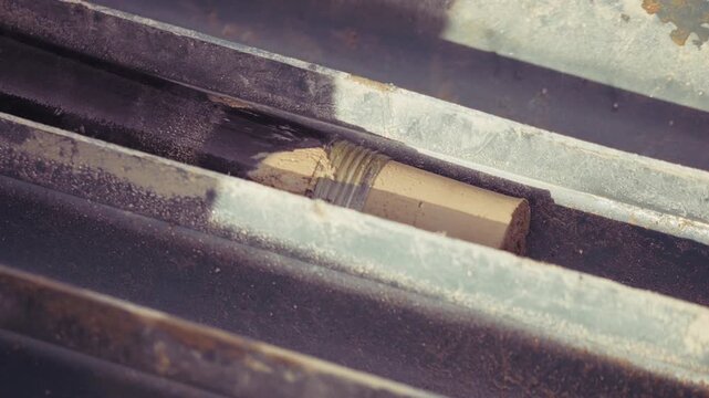 Authentic close-up video of soil core sample taken from drilling pipe during ground investigation. Real geotechnical engineering process showing underground soil composition. Natural industrial footag