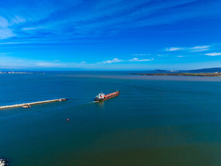 View of a cargo ship entering a harbor in Mexico during the daytime with clear sky and calm waters