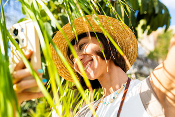 Girl with phone taking a photo of palm tree. Girl walking around old city in Arab country taking photos for social media.