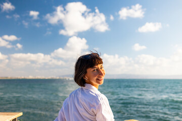 Close-up portrait of attractive woman, smiling, brunette, standing by the sea.