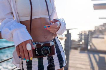 Girl with a camera. Beautiful tourist enjoying the sea view during her vacation and taking pictures with her camera.
