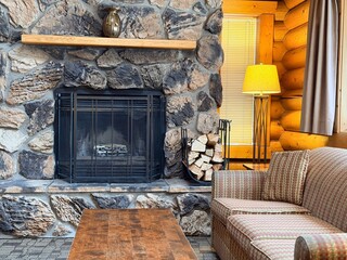 Naklejka premium Cozy room with fireplace, couch and wooden table