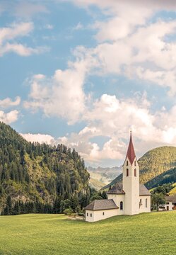 Small alpine village of Gramais with the parish church in warm evening sunlight on a hot summer day, surrounded by mountains in the Lechtal Alps, Tyrol, Austria.