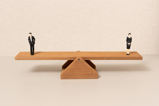 gender equality concept with man and woman figures on balanced wooden seesaw