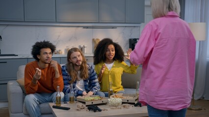 Four multiethnic friends men women playing pantomime game home party having fun smiling together...