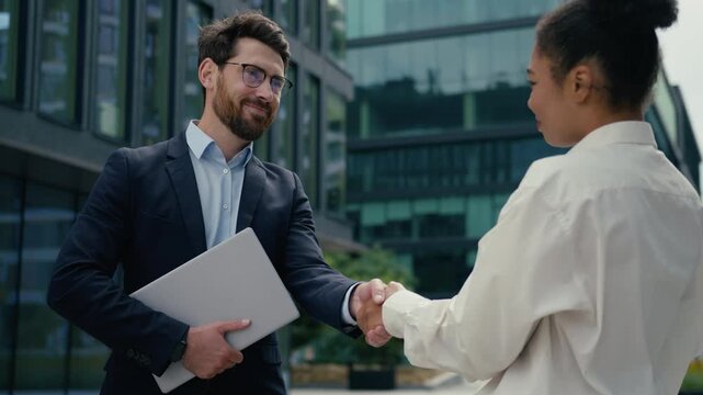 Happy two multiethnic business people shaking hands city partnership deal diversity Caucasian businessman African American businesswoman handshake recruitment agreement hiring success meeting outside