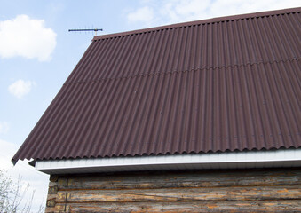modern construction of the roof with red metal siding to a wooden house in the garden