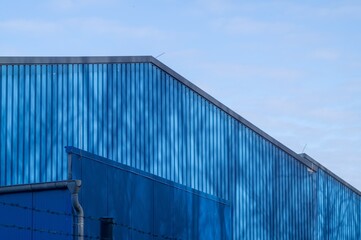 Fototapeta premium Blue corrugated metal building facade against sky