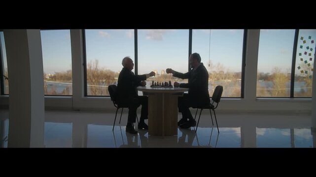 Middle Aged and Senior Businessmen Playing Chess for Money in Office