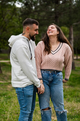 Obraz premium Happy couple holding hands laughing in green park