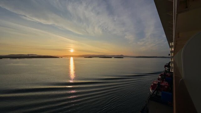 Sonnenuntergang der sich im Wasser spiegelt, mit leicht bedecktem Himmel, im Vordergrund sanfte Wellen, Bergen, Vestland, Norwegen, Europa