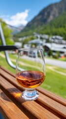 Fototapeta premium Glass of whiskey on wooden railing with mountain view background
