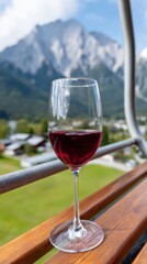 Fototapeta premium Glass of red wine on balcony with scenic mountain view in the background