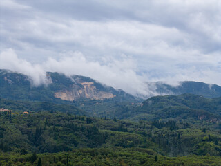 Obraz premium Greek island landscape with vast olive groves and a large mountain quarry. Misty clouds cover hills in rural Corfu, Greece