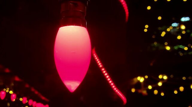 Festive Christmas lights with a central red C7 bulb and bokeh of yellow, blue, and green lights in the background.
