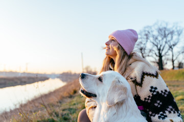 Smiling female, blonde Caucasian, sharing upward gaze with golden retriever at sunset © Iryna