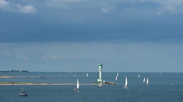 Mehrere Segelboote und Schiffe auf ruhigen blauen Meer unter einem bew&ouml;lkten Himmel mit einem Leuchtturm im Hintergrund, Leuchtturm Friedrichsort, Kieler Bucht, F&ouml;rde, Ostsee