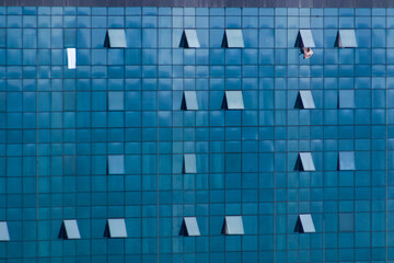 Contemporary blue glass building facade with geometric window pattern in Batumi, Georgia. Modern urban architecture featuring reflective surfaces and open windows in the coastal Black Sea city.  © Ruslan