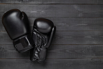 Black boxing gloves on wooden background, top view