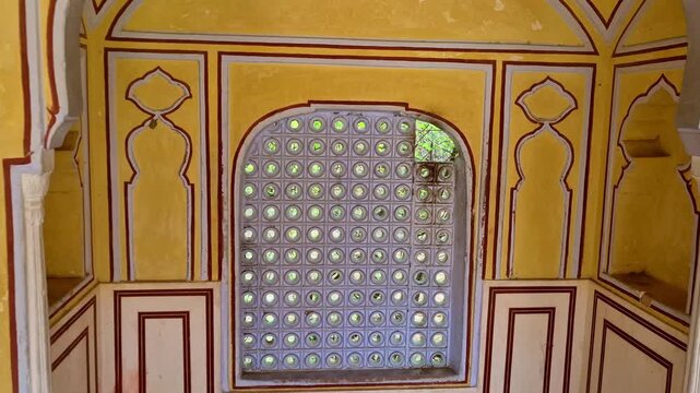 An elegant arched alcove inside a historic Jaipur palace corridor features a perforated stone jali window. Soft daylight passes through the patterned openings.