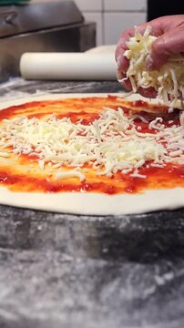 A person is making a pizza with cheese and sauce
