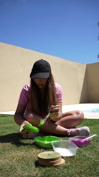 Young woman painting a wooden tejo in a sunny garden