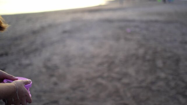 Woman throwing tejo pieces playing on the beach sand